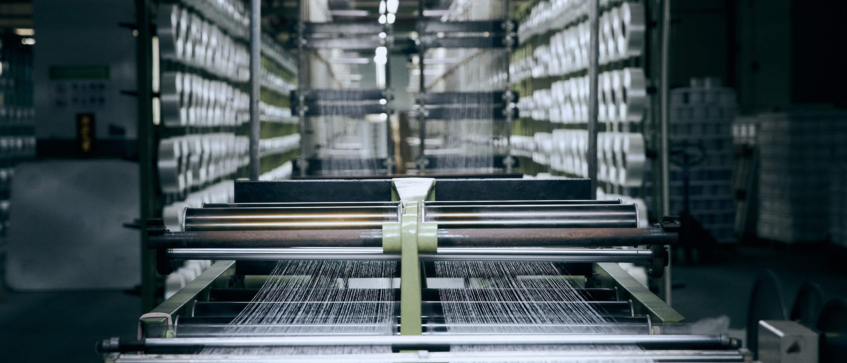 MUDDY VIBE textile factory with machines and numerous rolls of yarn.