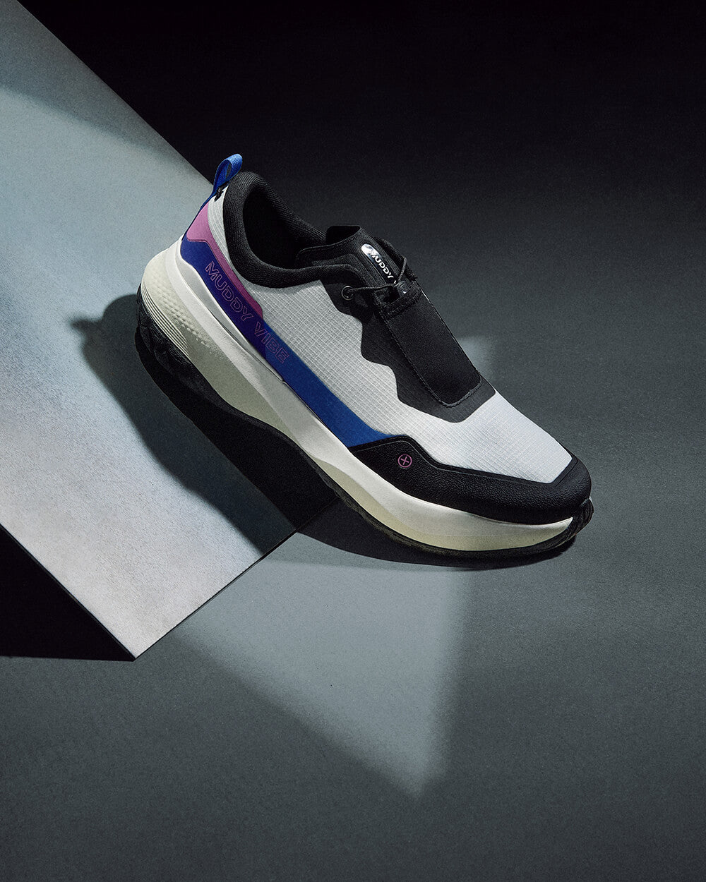 MUDDY VIBE S-16 Aurora White low-top hiking shoes on a dark grey board in soft lighting, side view on a grey background.