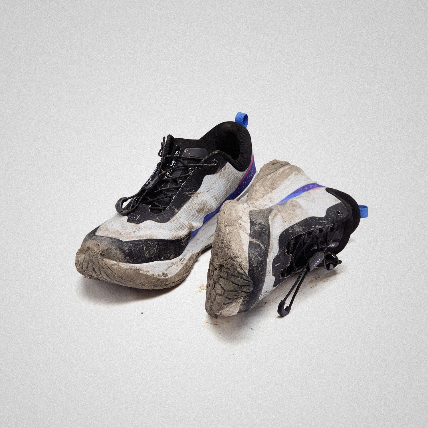 MUDDY VIBE Si-14 low-top Aurora White shoes with visible mud, black, blue and purple accents, 45 degree side view on a white background.