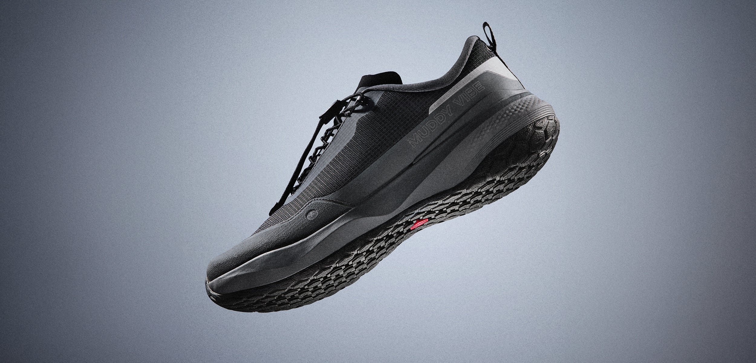 MUDDY VIBE Si-14 low-top Tide Rock hiking shoe with visible sole, black and grey accents, mid-air against a soft shadow background.