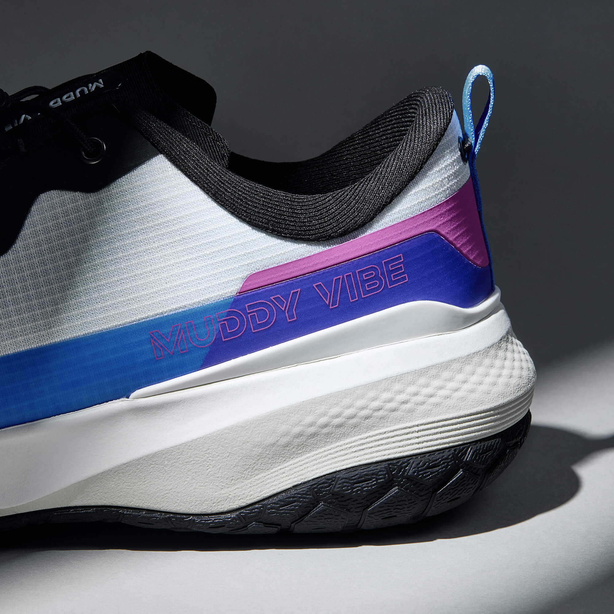 MUDDY VIBE S-16 Aurora White low-top hiking shoe with black, blue, and purple accents, heel logo view on a soft shadow background.