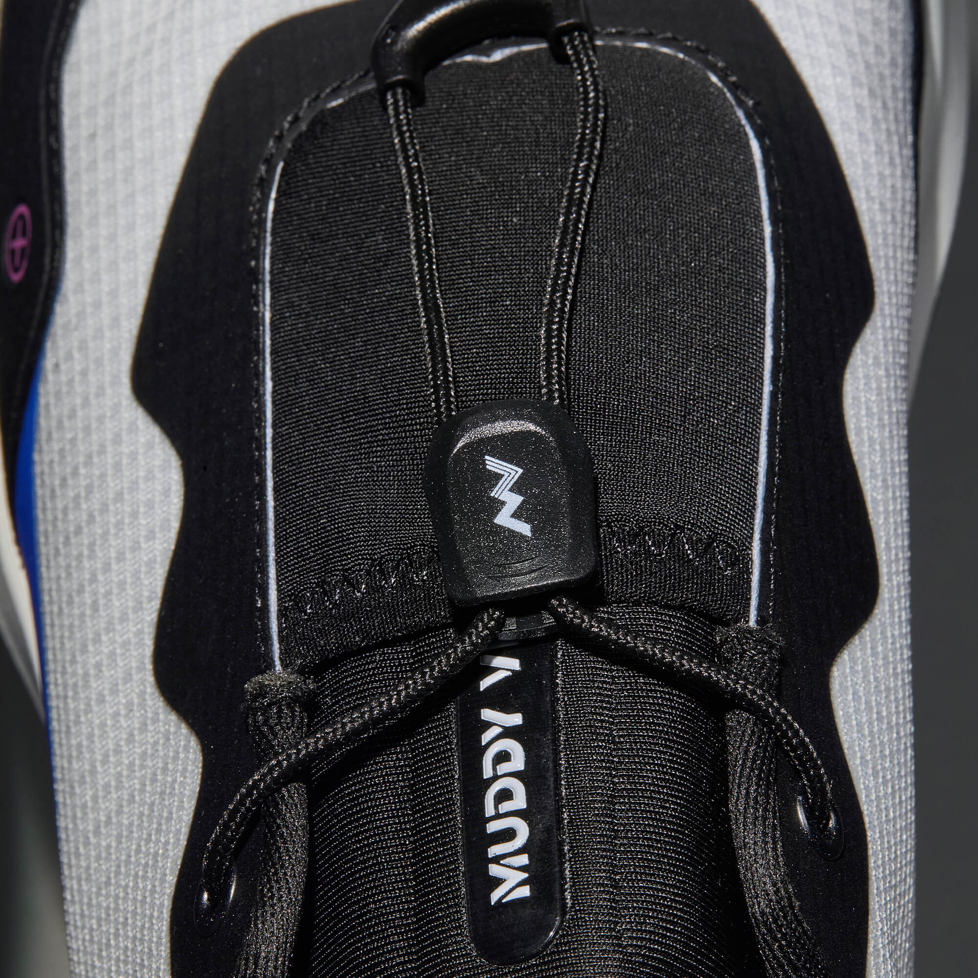 MUDDY VIBE S-16 Aurora White low-top hiking shoe with black and blue accents, lace detail view on a soft shadow background.