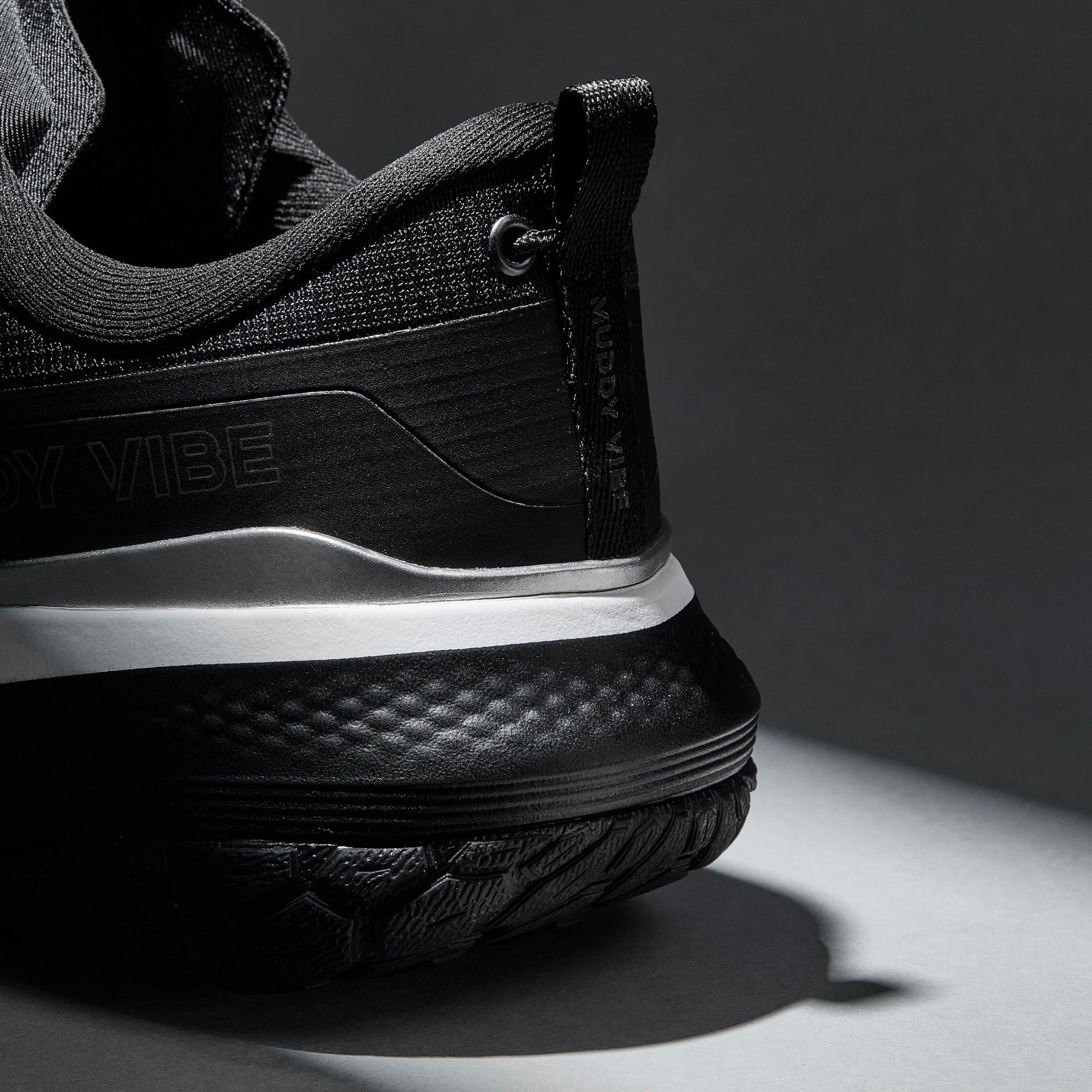 MUDDY VIBE S-16 Ridge Snow low-top hiking shoe with black and white accents, heel detail view on a soft shadow background.