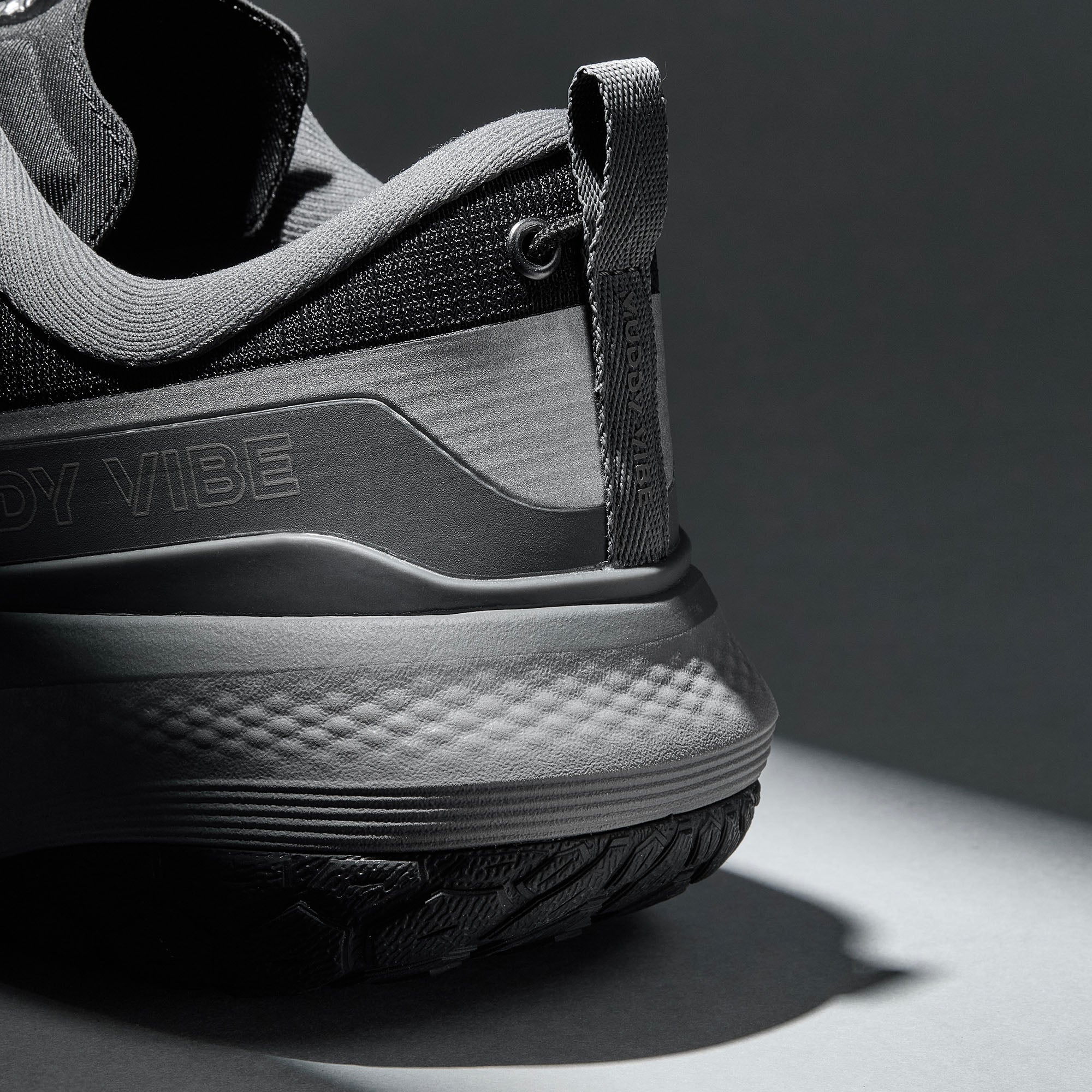 MUDDY VIBE S-16 Tide Rock low-top hiking shoe with black and grey accents, heel detail view on a soft shadow background.