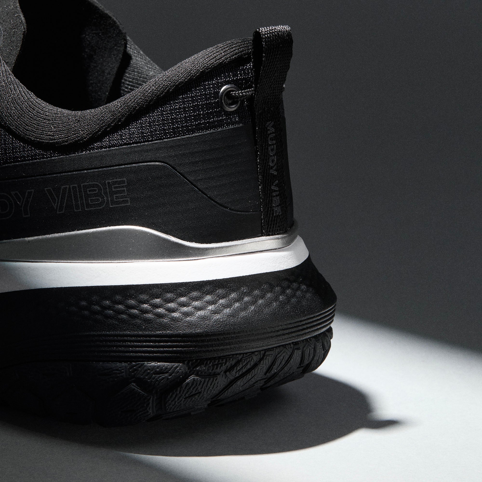 MUDDY VIBE Si-14 Ridge Snow low-top hiking shoe with black and white accents, heel detail view on a soft shadow background.