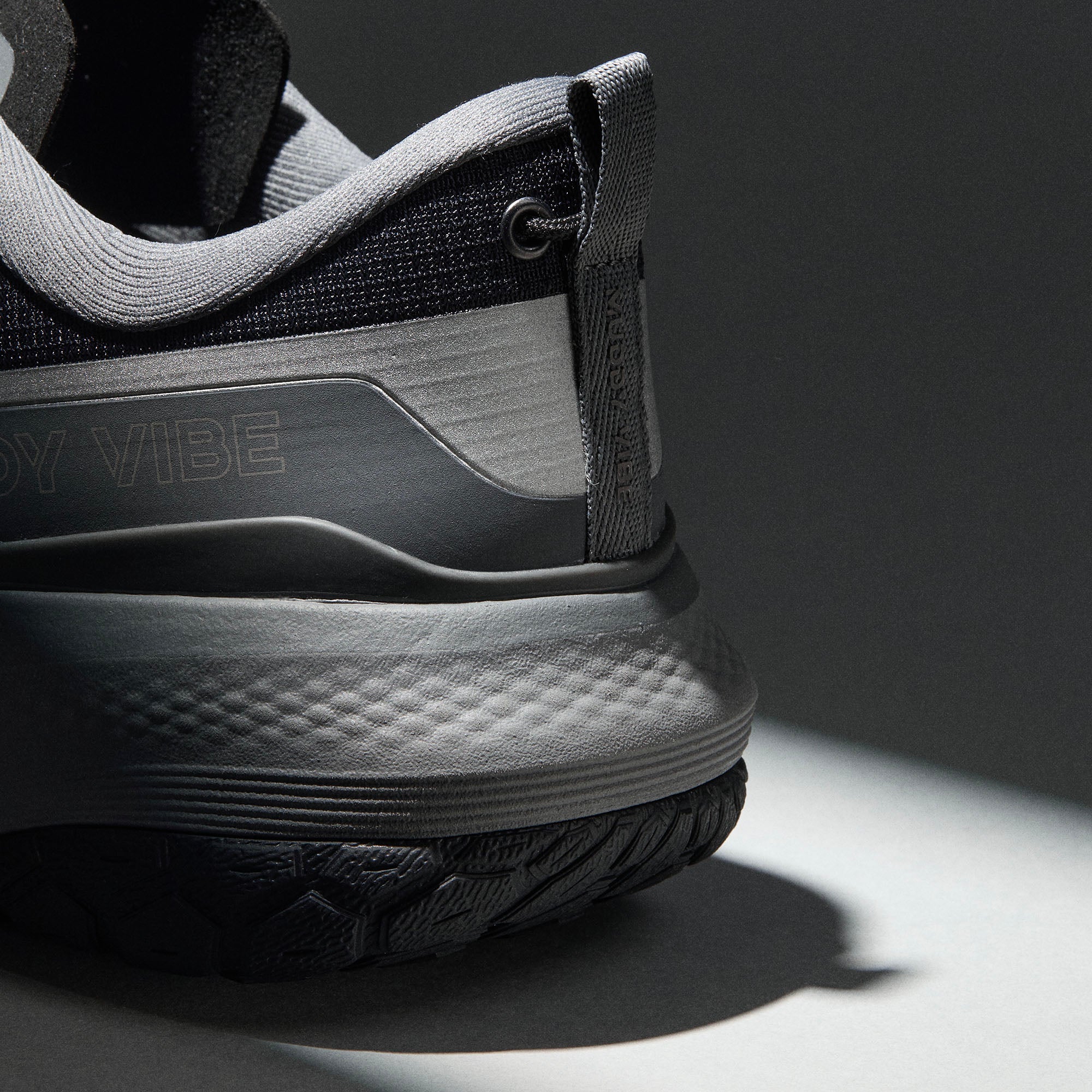 MUDDY VIBE Si-14 Tide Rock low-top hiking shoe with black and grey accents, heel detail view on a soft shadow background.