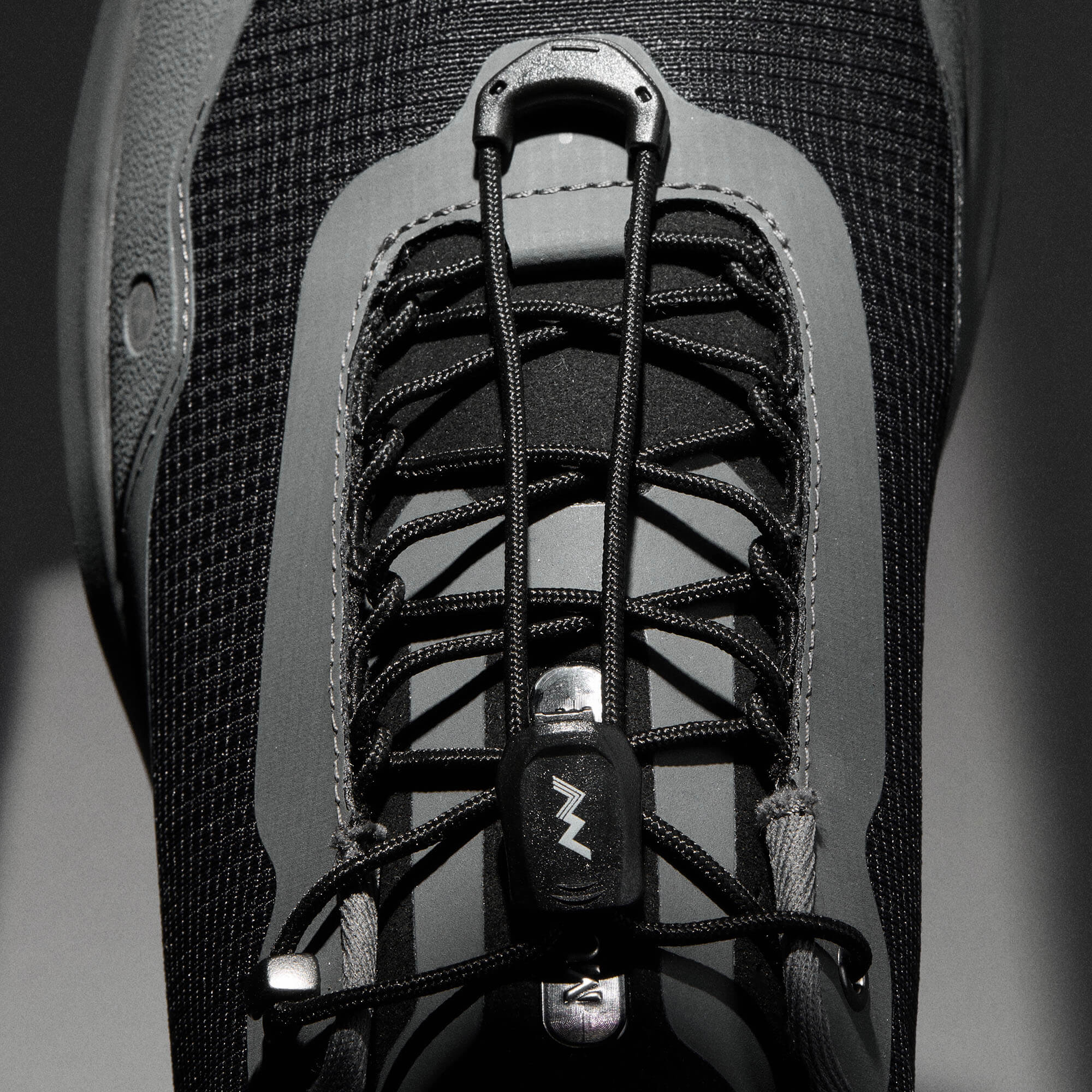 MUDDY VIBE Si-14 Tide Rock low-top hiking shoe with black and grey accents, lace detail view on a soft shadow background.