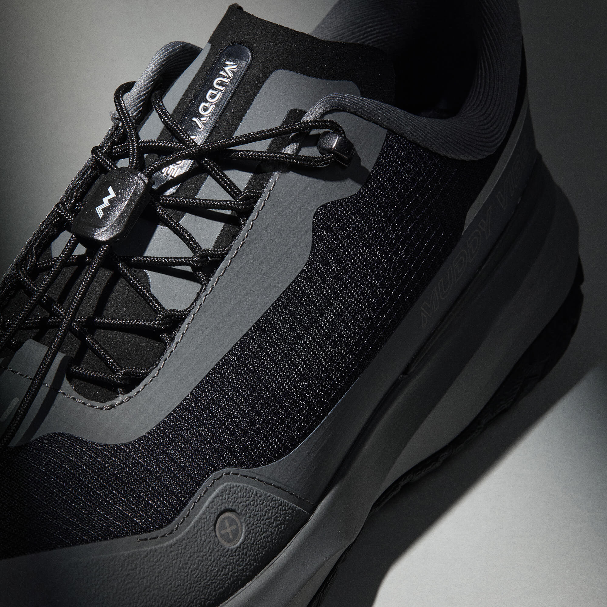 MUDDY VIBE Si-14 Tide Rock low-top hiking shoe with black and grey accents, laces view on a soft shadow background.