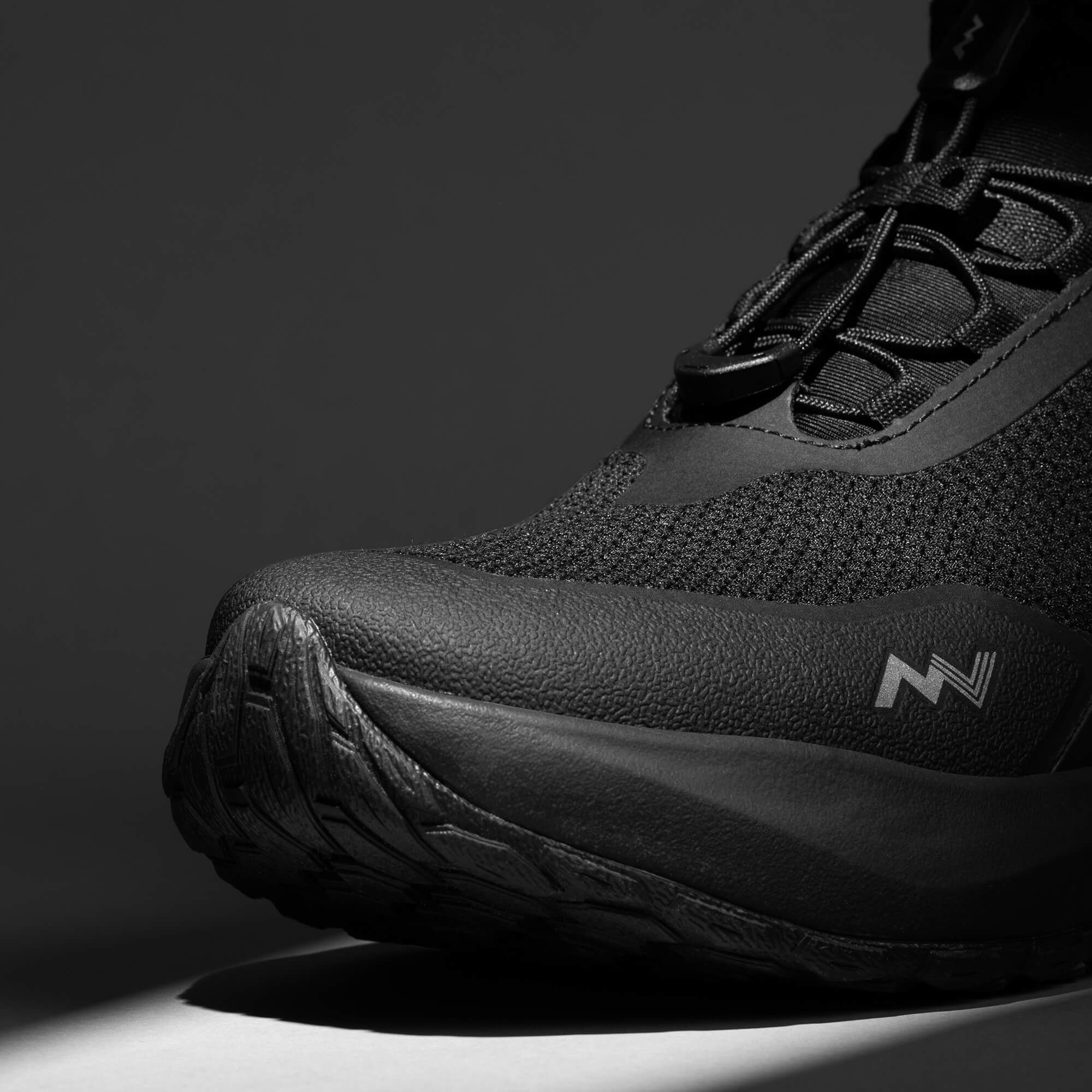 MUDDY VIBE Zn-30 Black Summit mid-top hiking shoe with with all-black trim, front view on a soft shadow background.