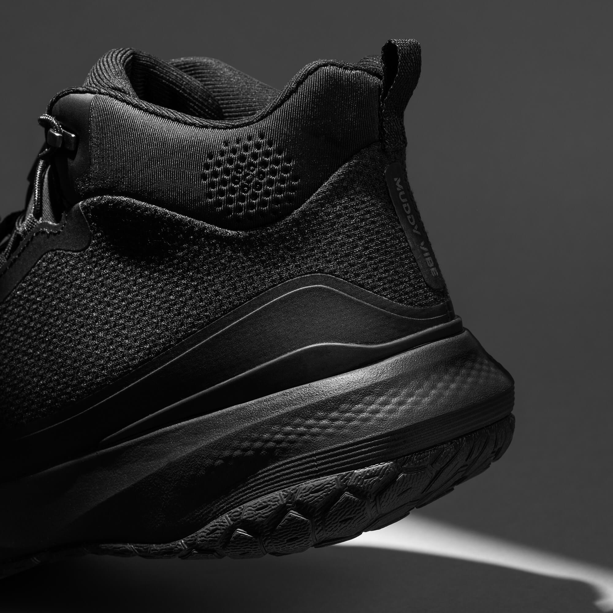 MUDDY VIBE Zn-30 Black Summit mid-top hiking shoe with with all-black trim, heel detail view on a soft shadow background.