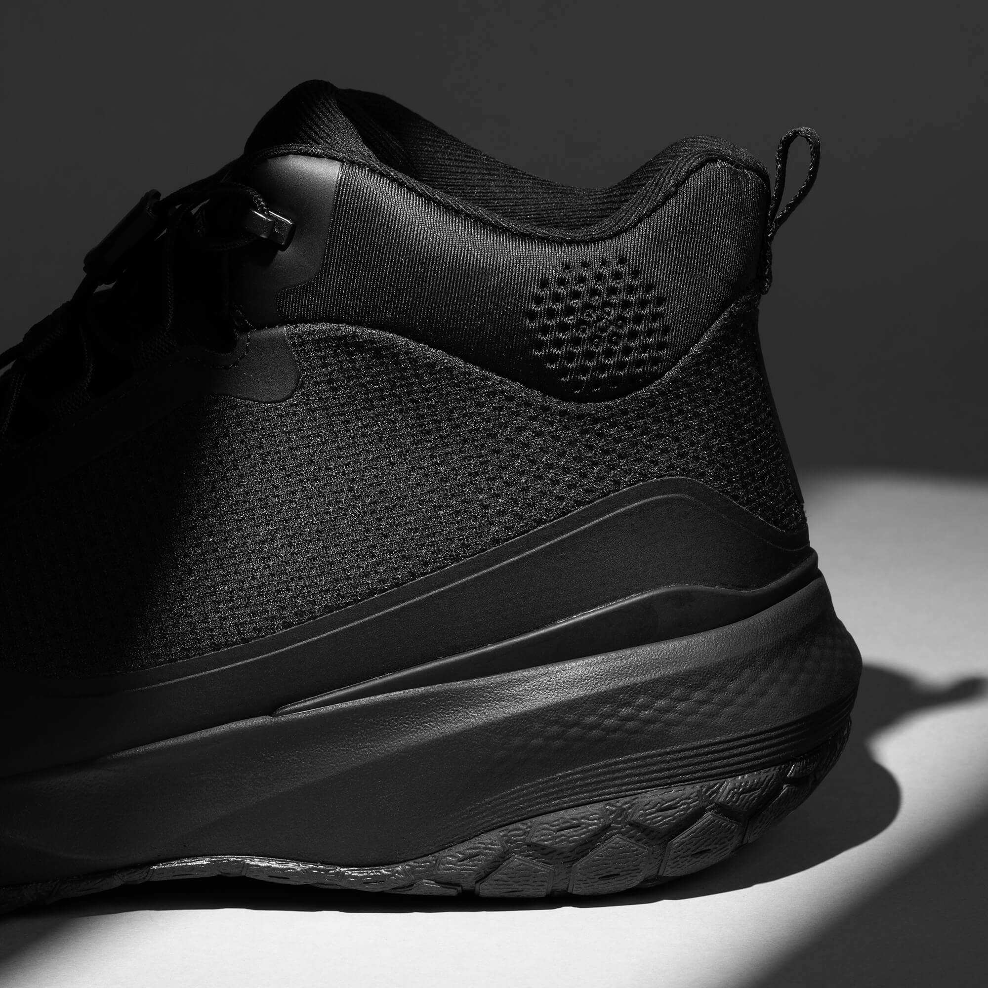 MUDDY VIBE Zn-30 Black Summit mid-top hiking shoe with with all-black trim, heel logo view on a soft shadow background.