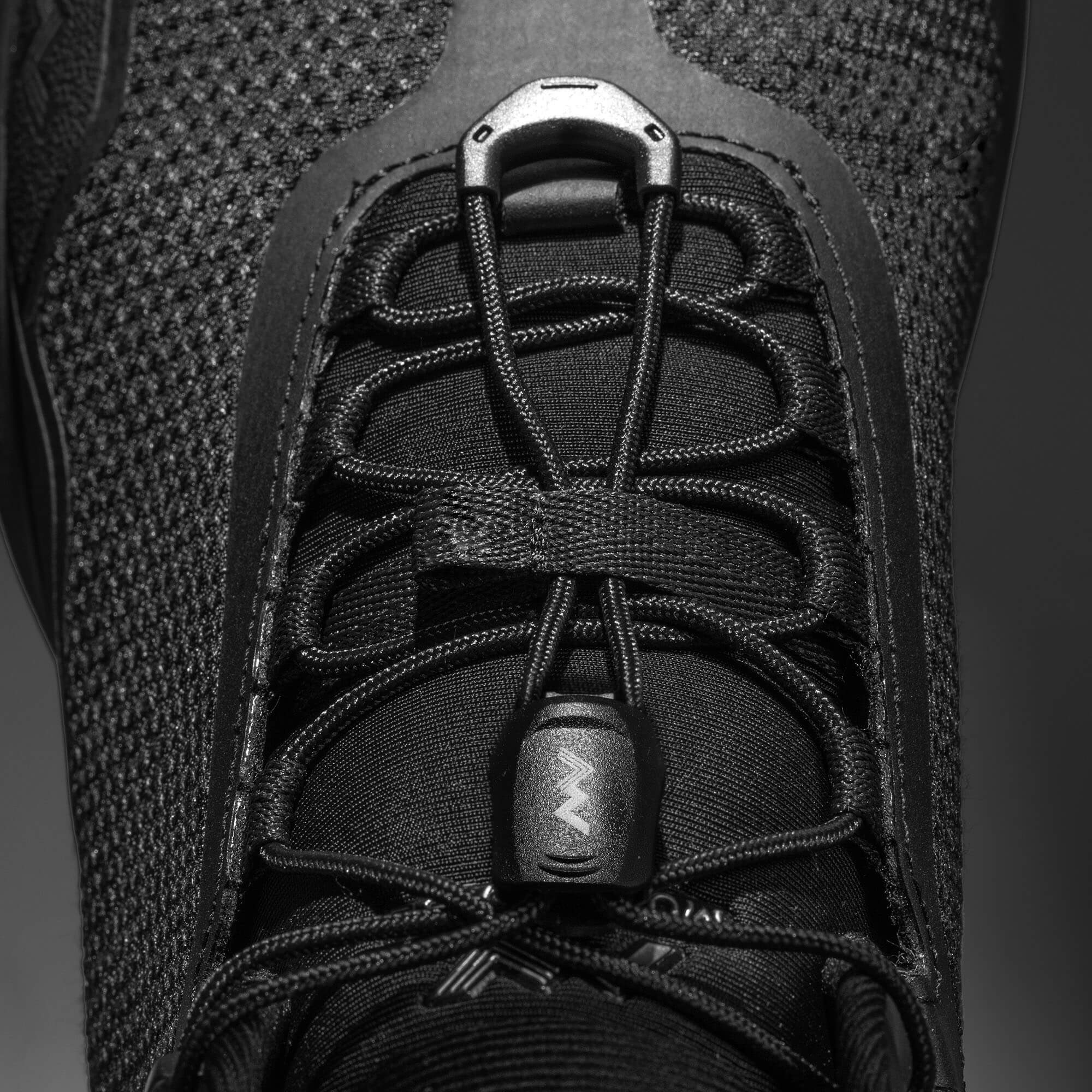 MUDDY VIBE Zn-30 Black Summit mid-top hiking shoe with with all-black trim, lace detail view on a soft shadow background.