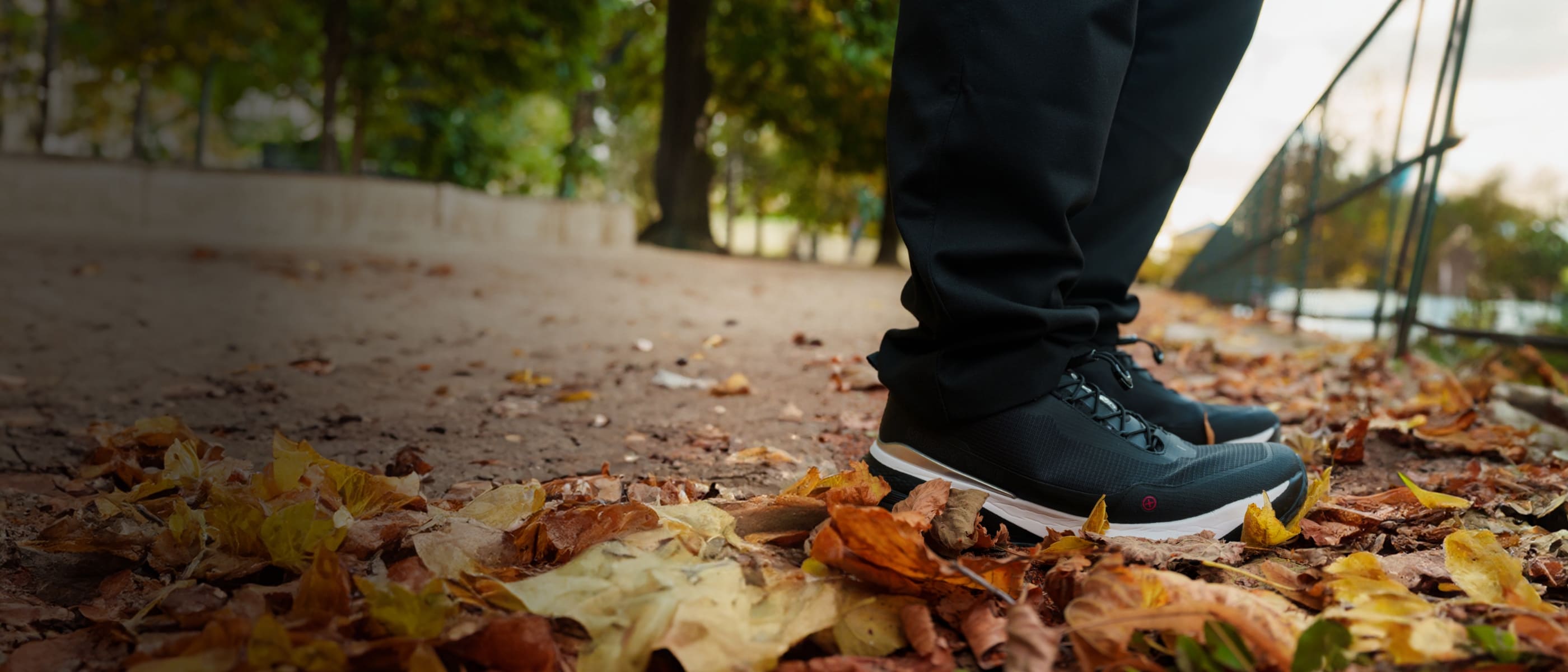 Si-14 lightweight black walking shoes for men, standing on a trail covered in leaves
