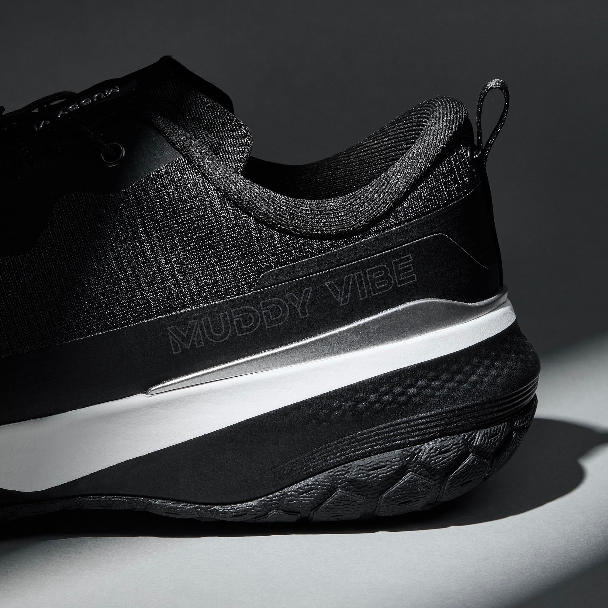 MUDDY VIBE S-16 Ridge Snow low-top hiking shoe with black and white accents, heel logo view on a soft shadow background.