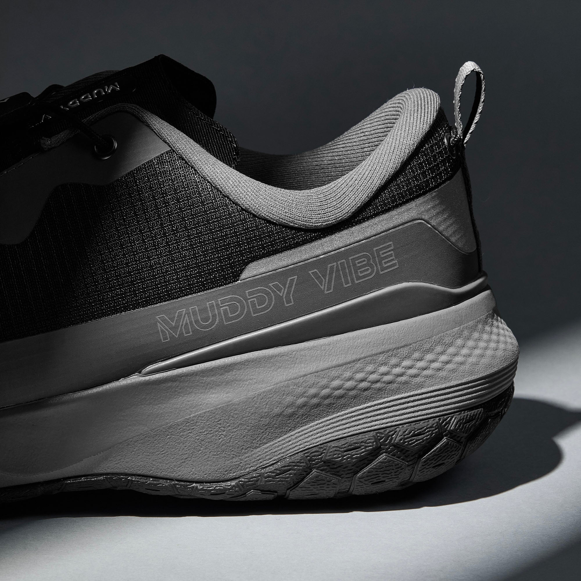 MUDDY VIBE S-16 Tide Rock low-top hiking shoe with black and grey accents, heel logo view on a soft shadow background.