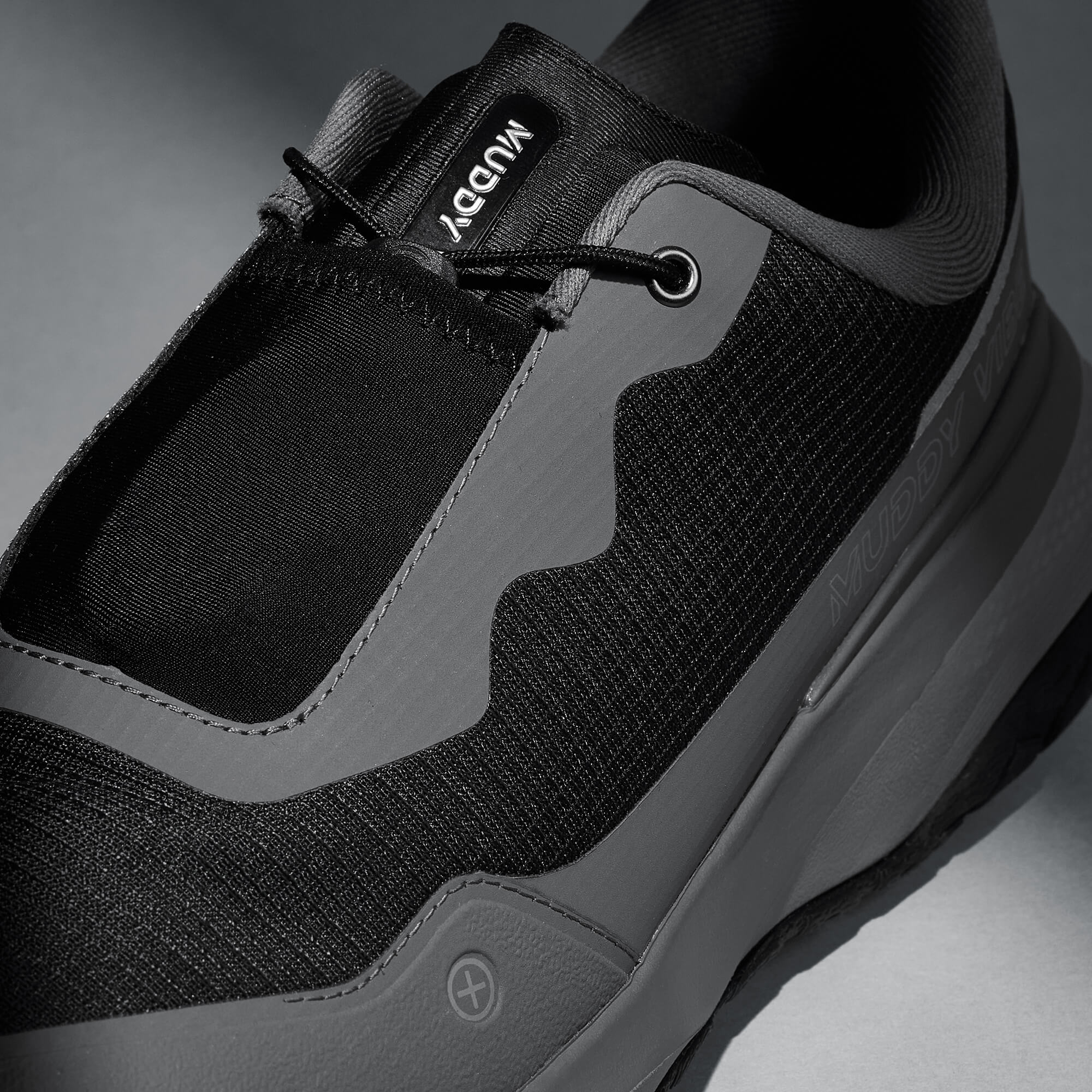 MUDDY VIBE S-16 Tide Rock low-top hiking shoe with black and grey accents, laces detail view on a soft shadow background.